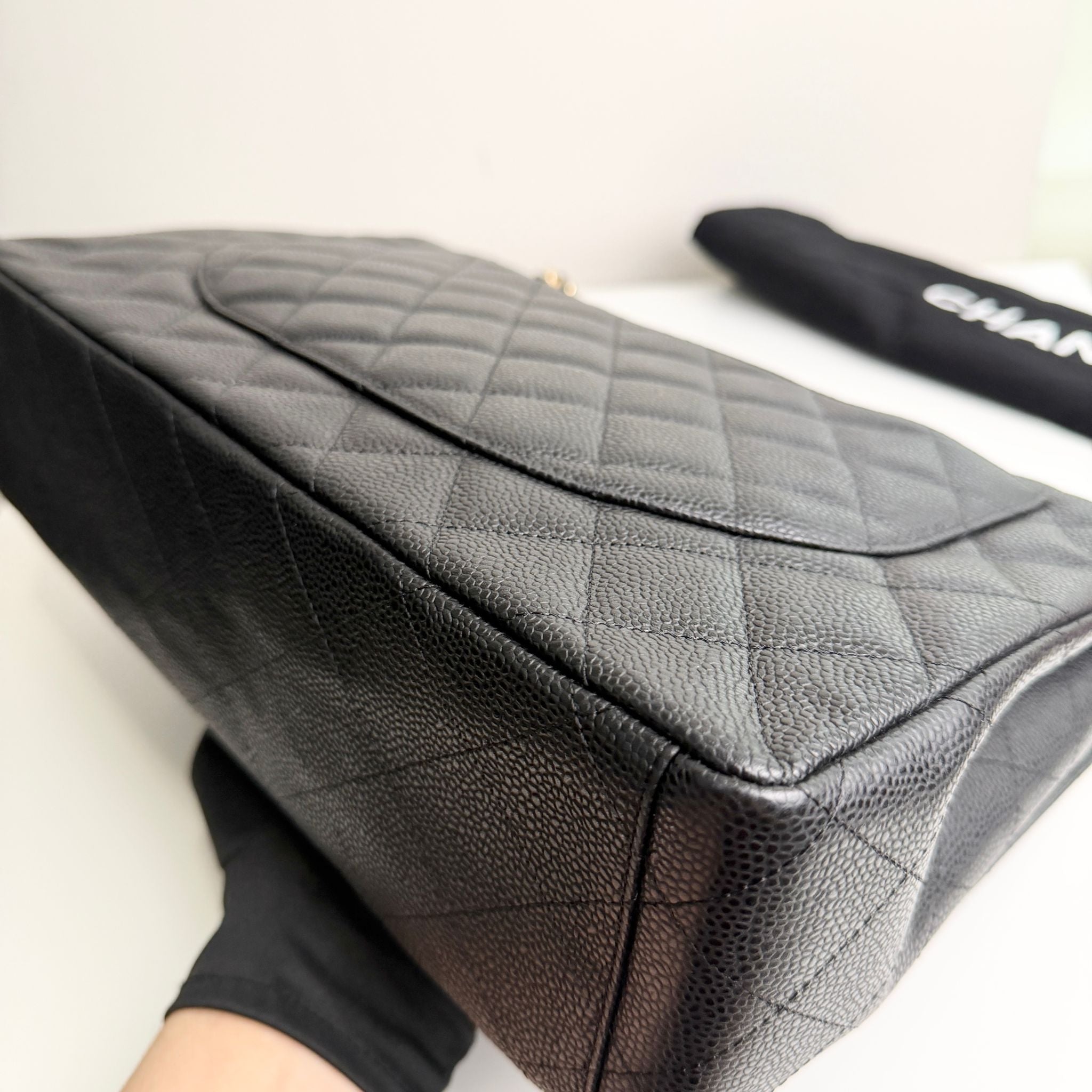 Black quilted handbag with a visible brand logo on a white background
