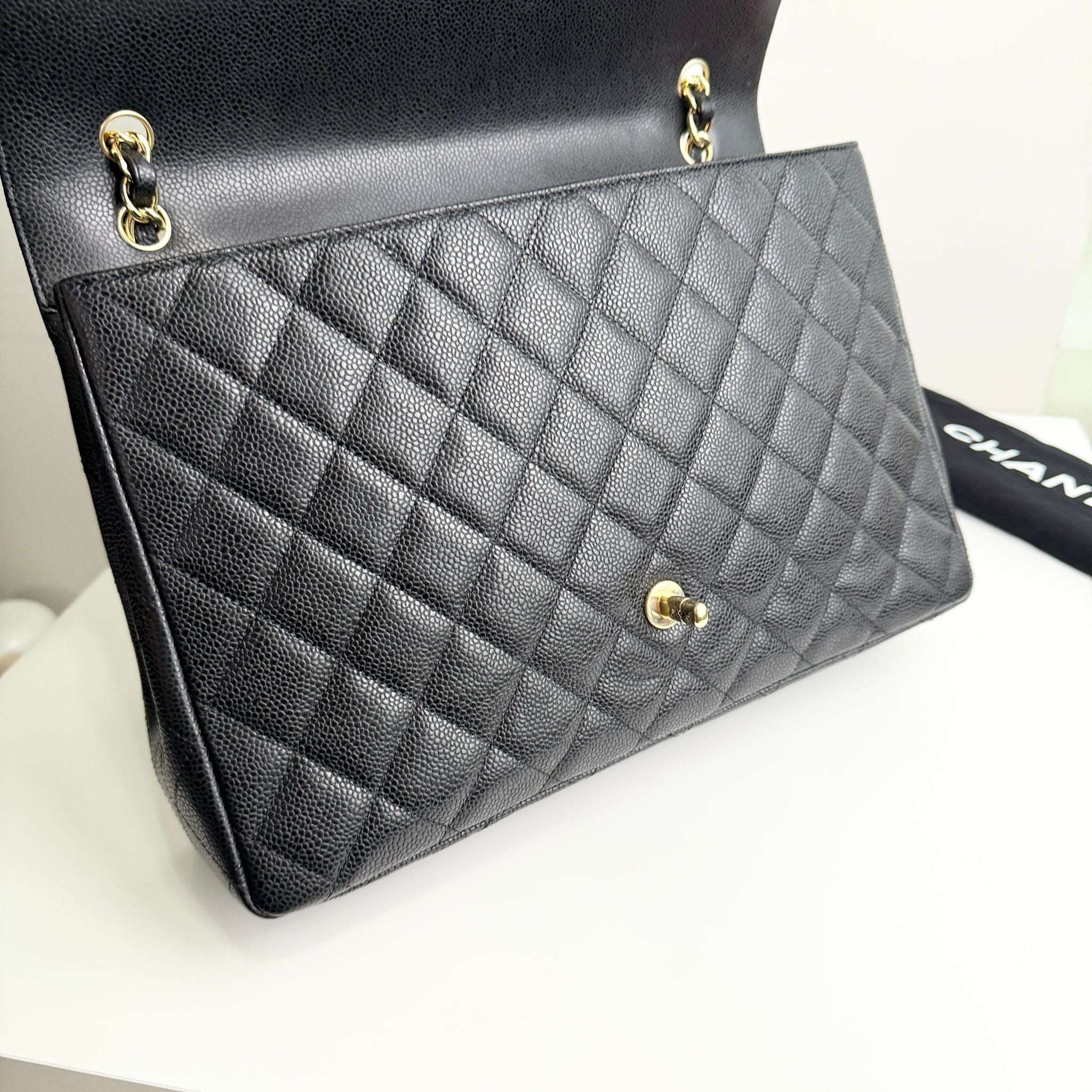 Black quilted handbag with gold hardware on a light gray background
