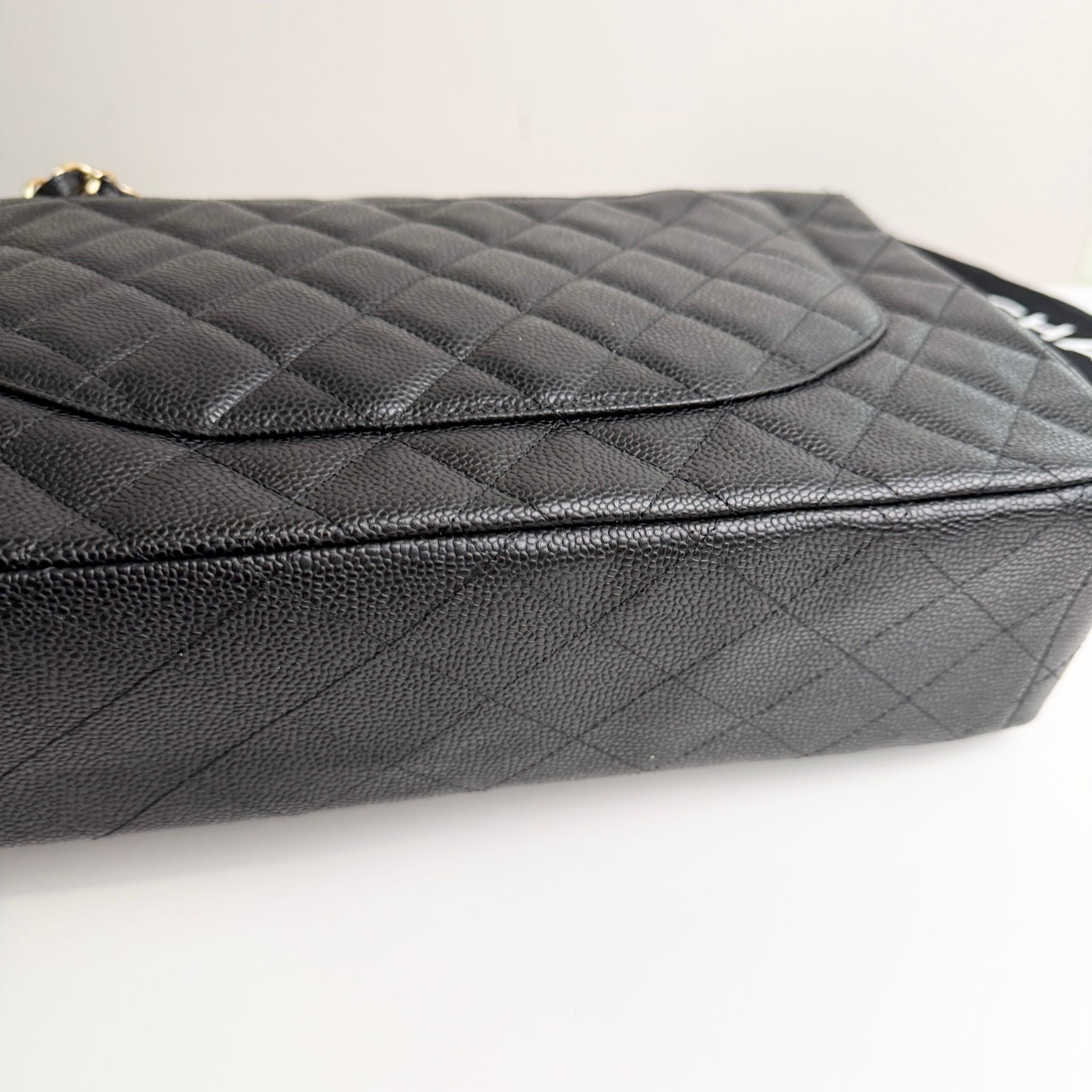 Black quilted handbag on a light gray background