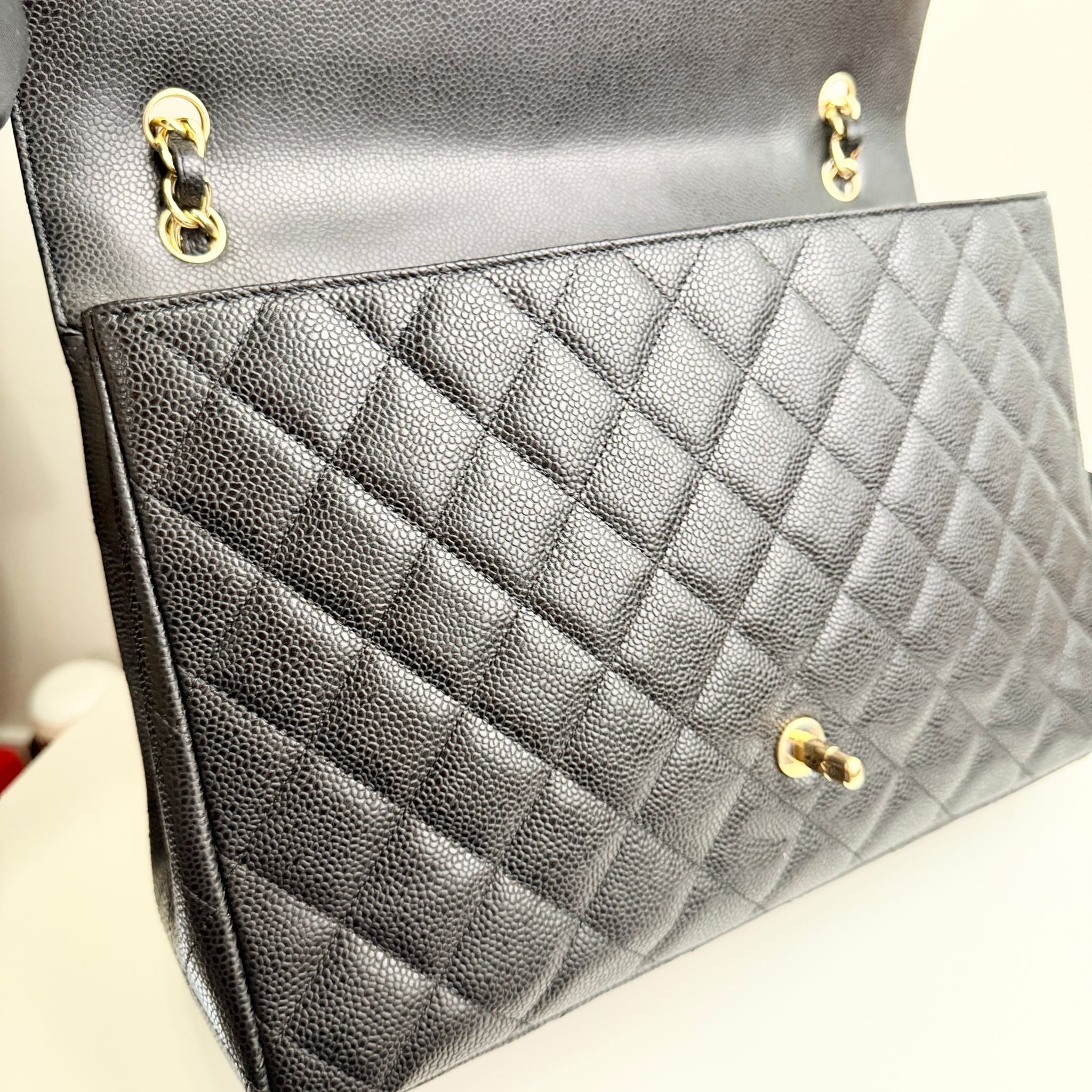 Close-up of a quilted black handbag with gold hardware on a neutral background