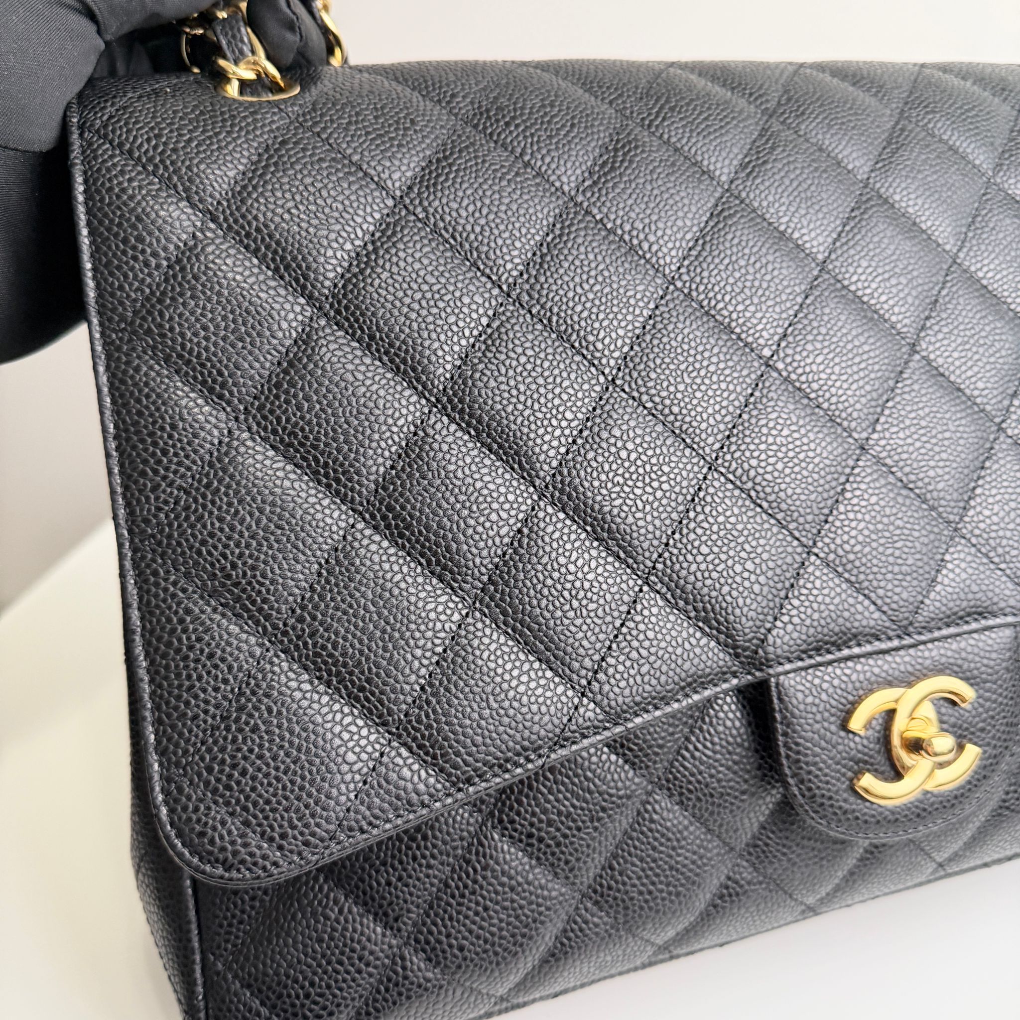 Gray quilted handbag with gold Chanel logo on a light background