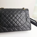 将图片加载到图库查看器，Black quilted handbag with gold hardware on a white surface, with a black Chanel dust bag partially visible.
