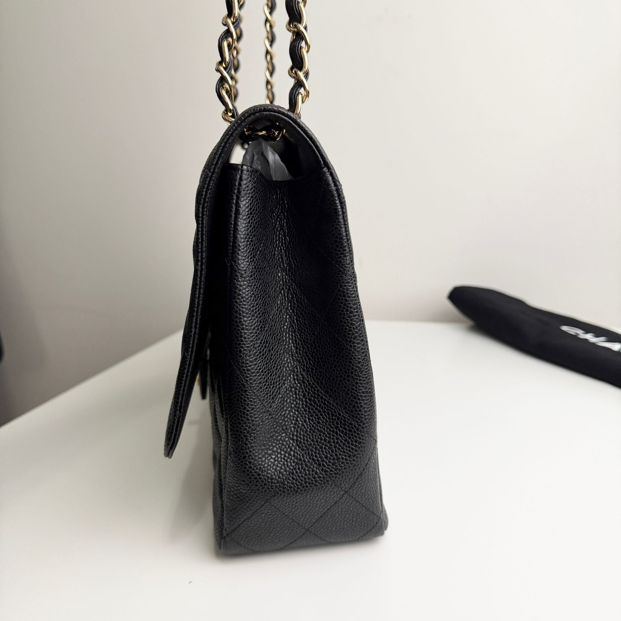 Black leather handbag with chain strap on a white surface