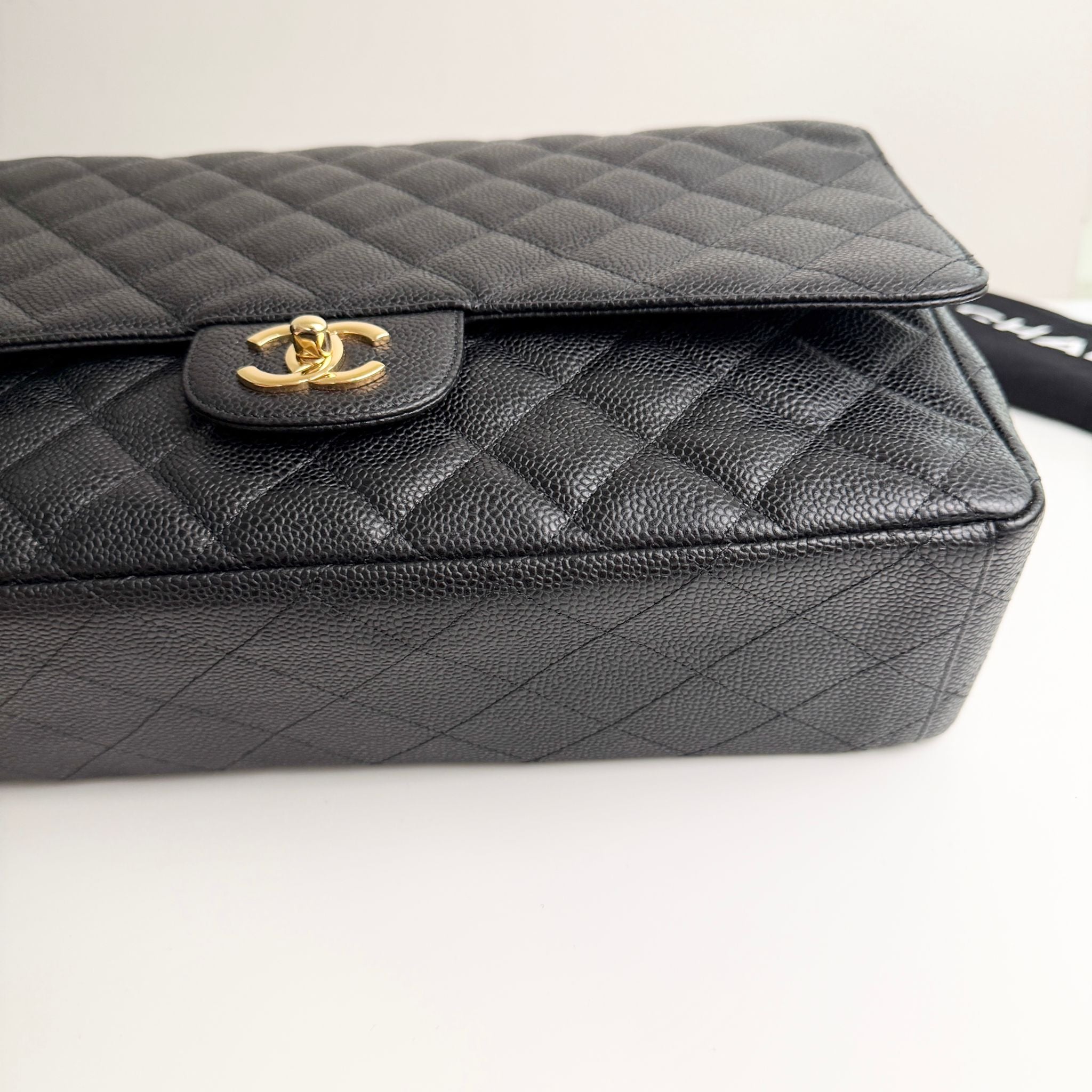 Black quilted handbag with gold clasp on a white background