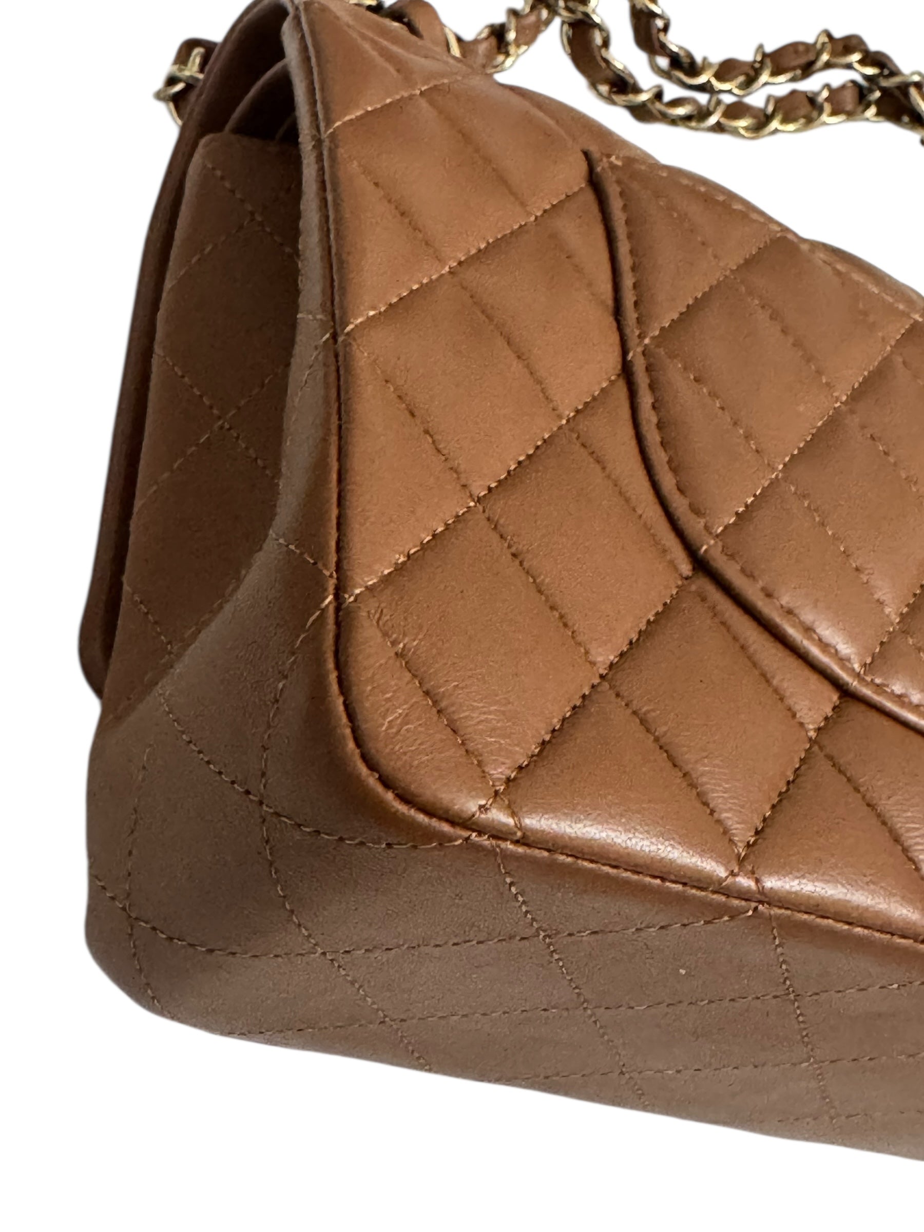Brown quilted handbag with a gold chain on a white background