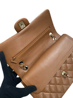将图片加载到图库查看器，Brown leather handbag with gold hardware held by a gloved hand on a white background
