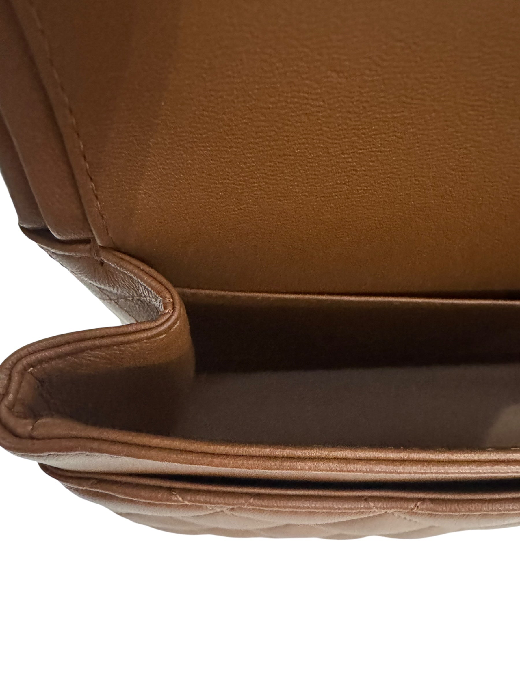 Close-up of a brown leather bag with a quilted pattern on a white background