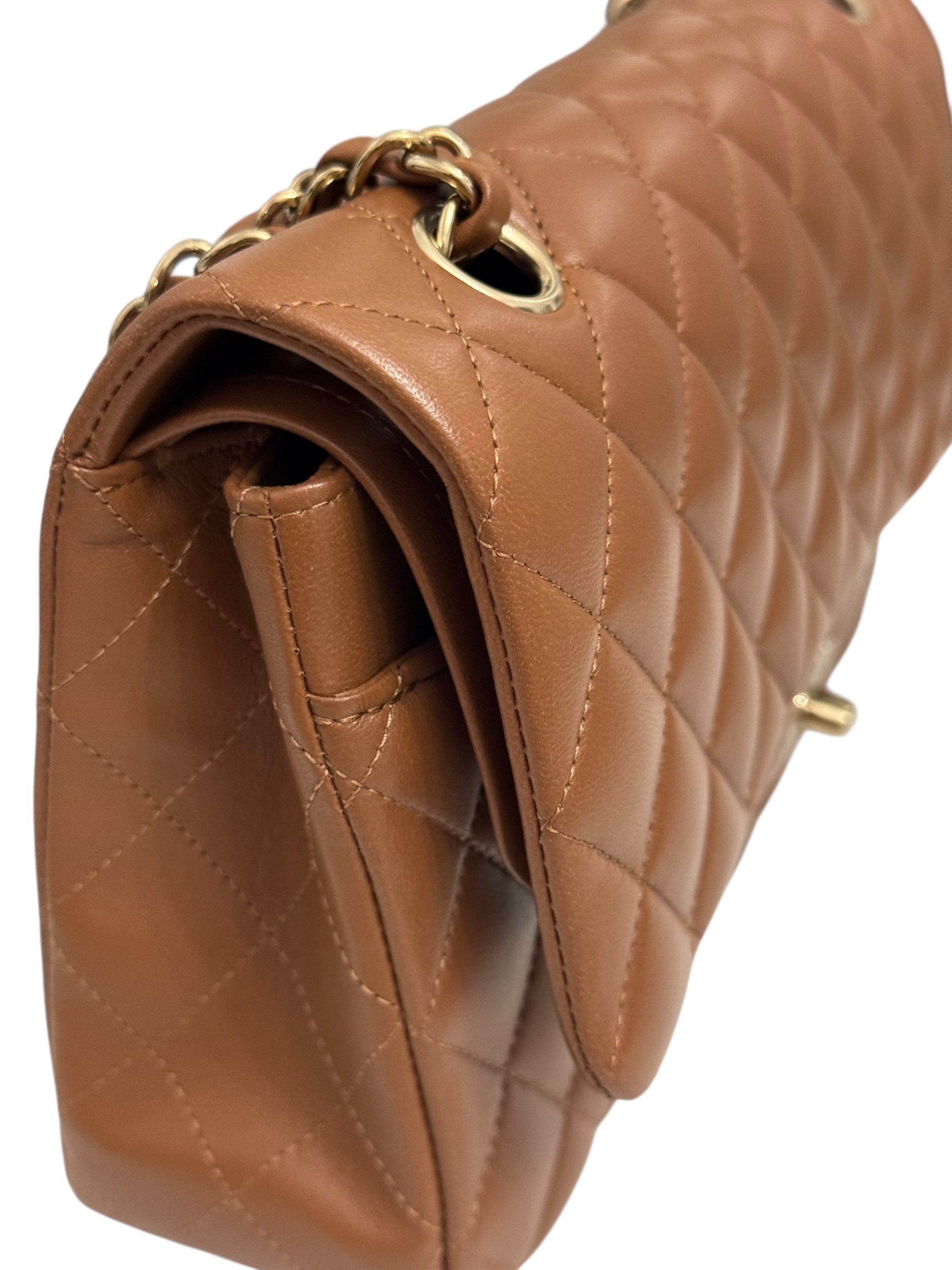 Close-up of a brown quilted handbag with gold chain detail on a white background