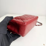 将图片加载到图库查看器，Red quilted handbag held by a gloved hand on a white background
