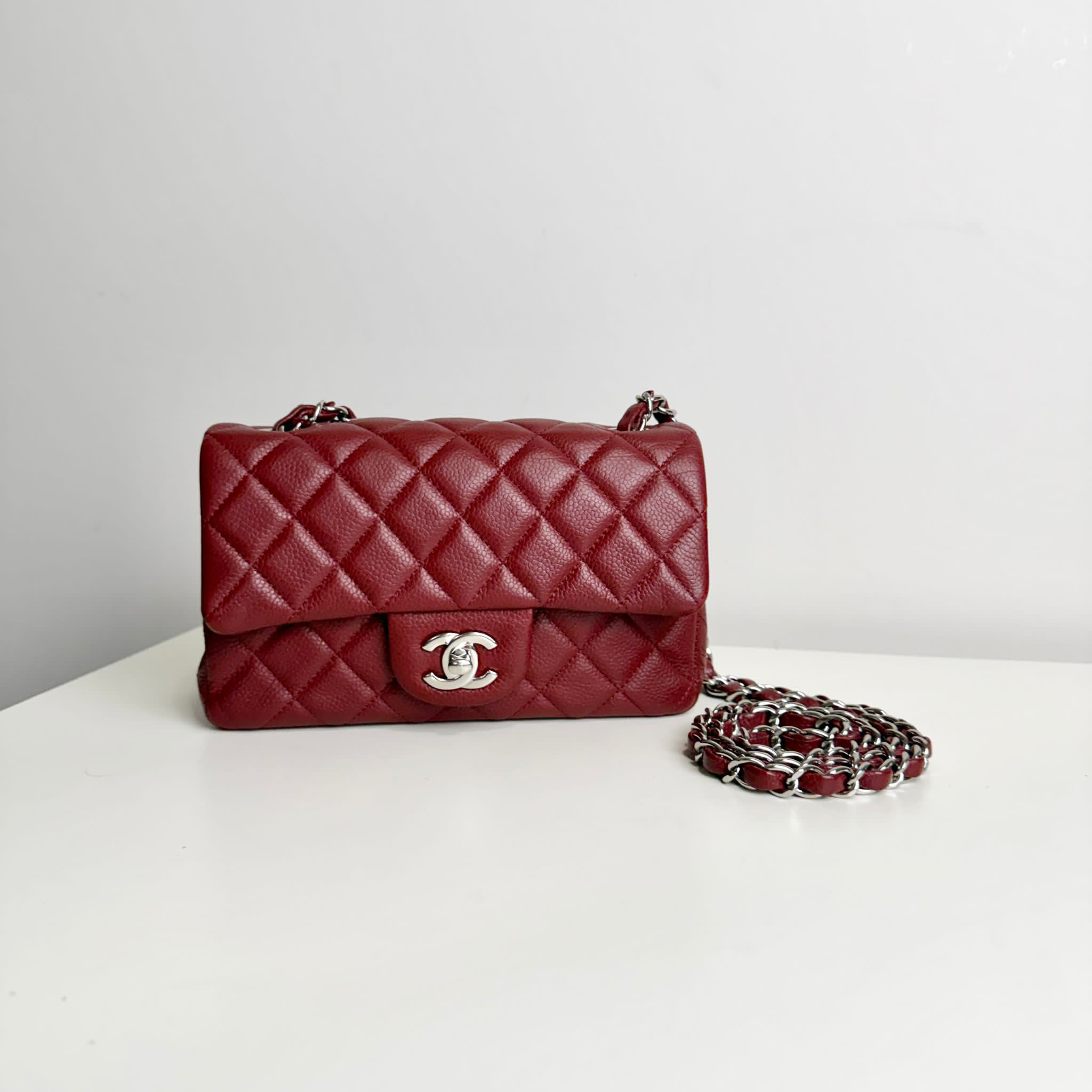 Red quilted handbag with chain detail on a white surface