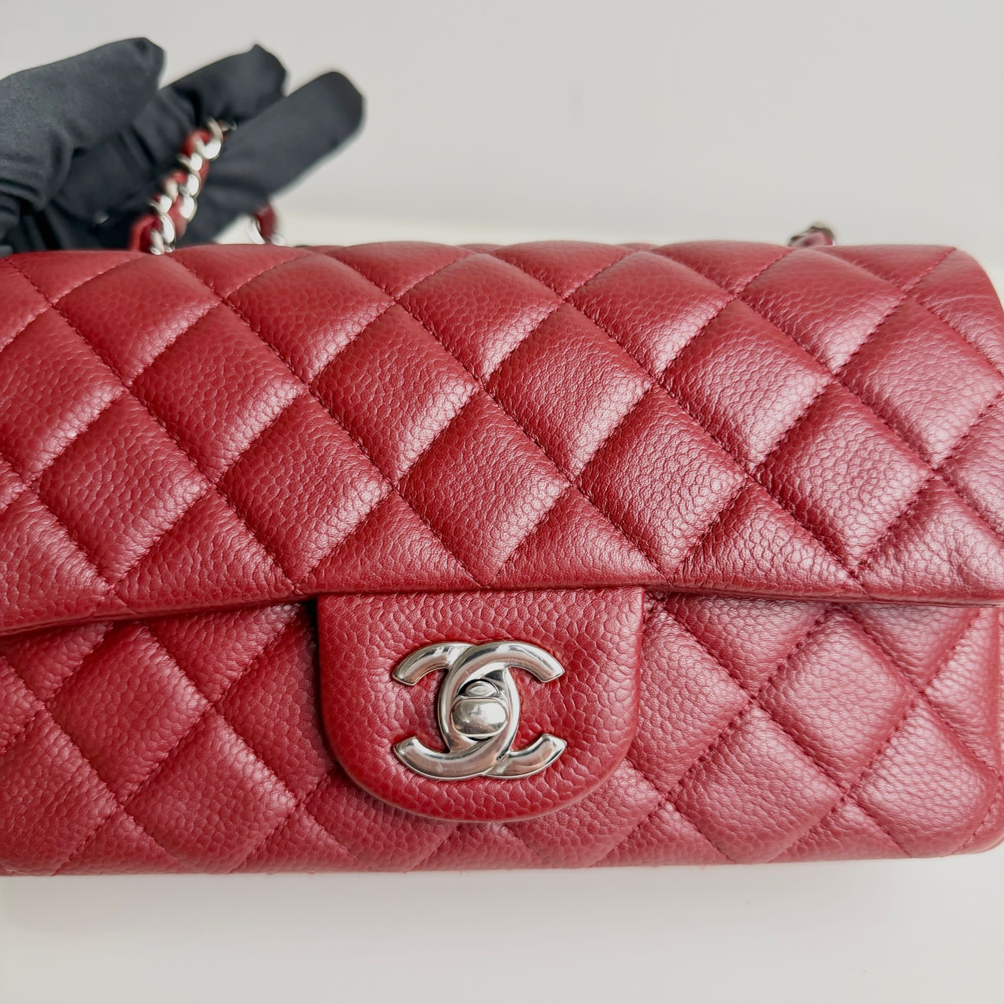 Red quilted handbag with Chanel logo on a light gray background