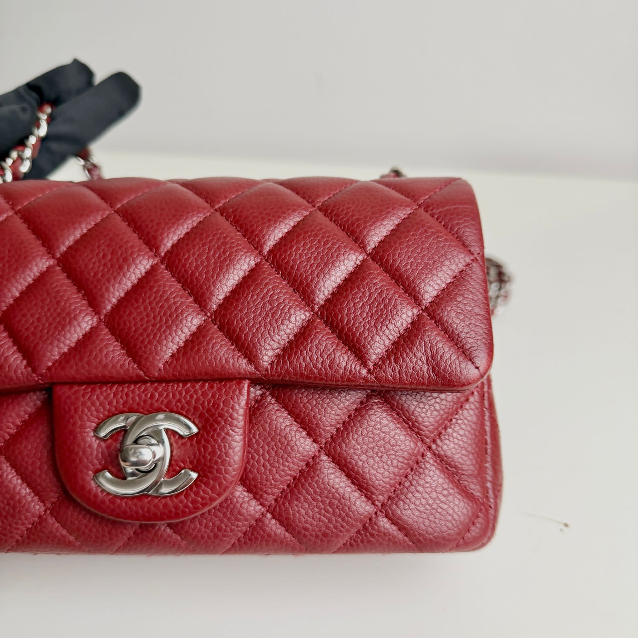 Red quilted handbag with silver Chanel logo on a light background