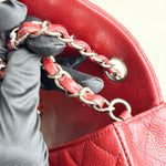 将图片加载到图库查看器，Red leather handbag with silver chain handle held by a gloved hand.
