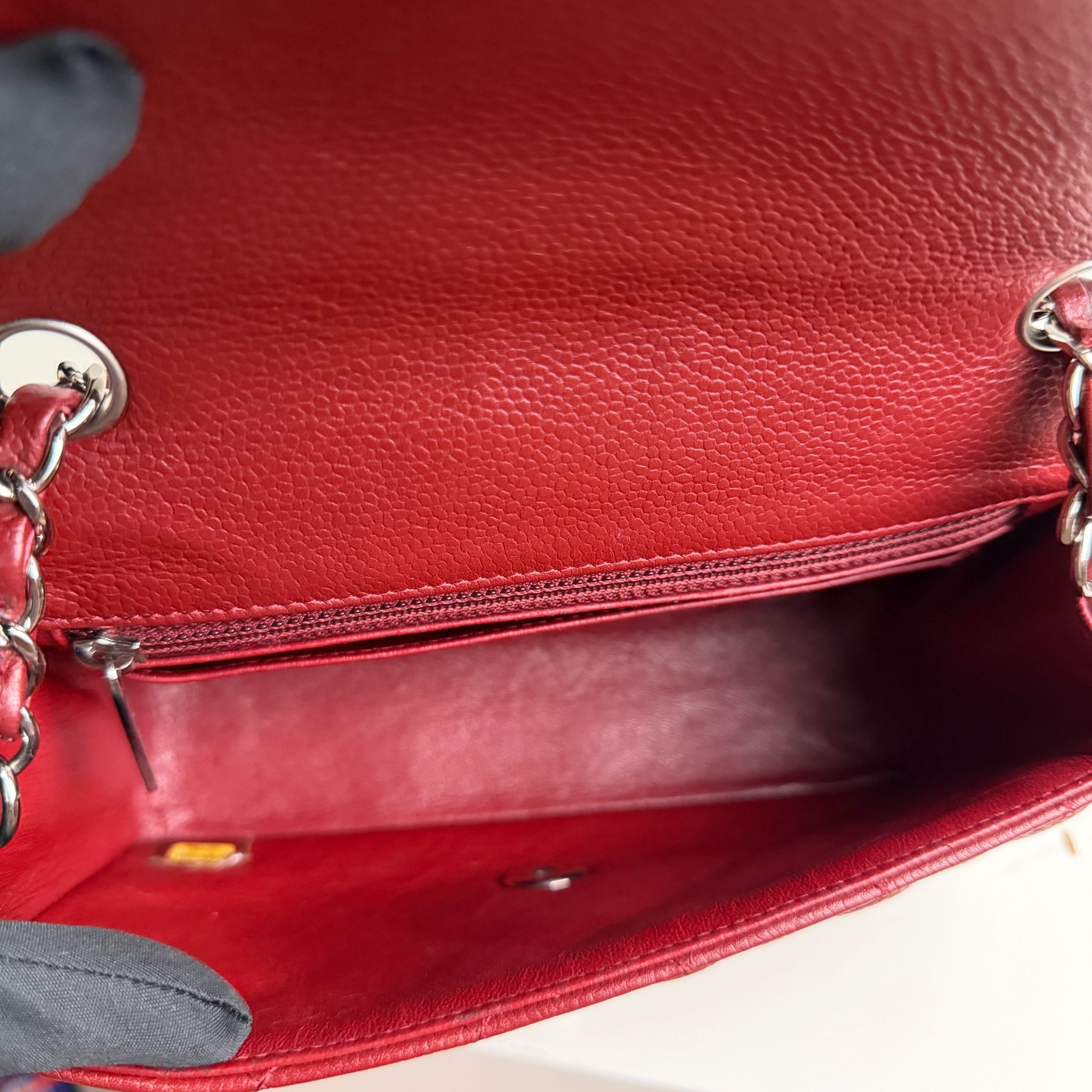 Close-up of a red leather handbag with a chain detail.