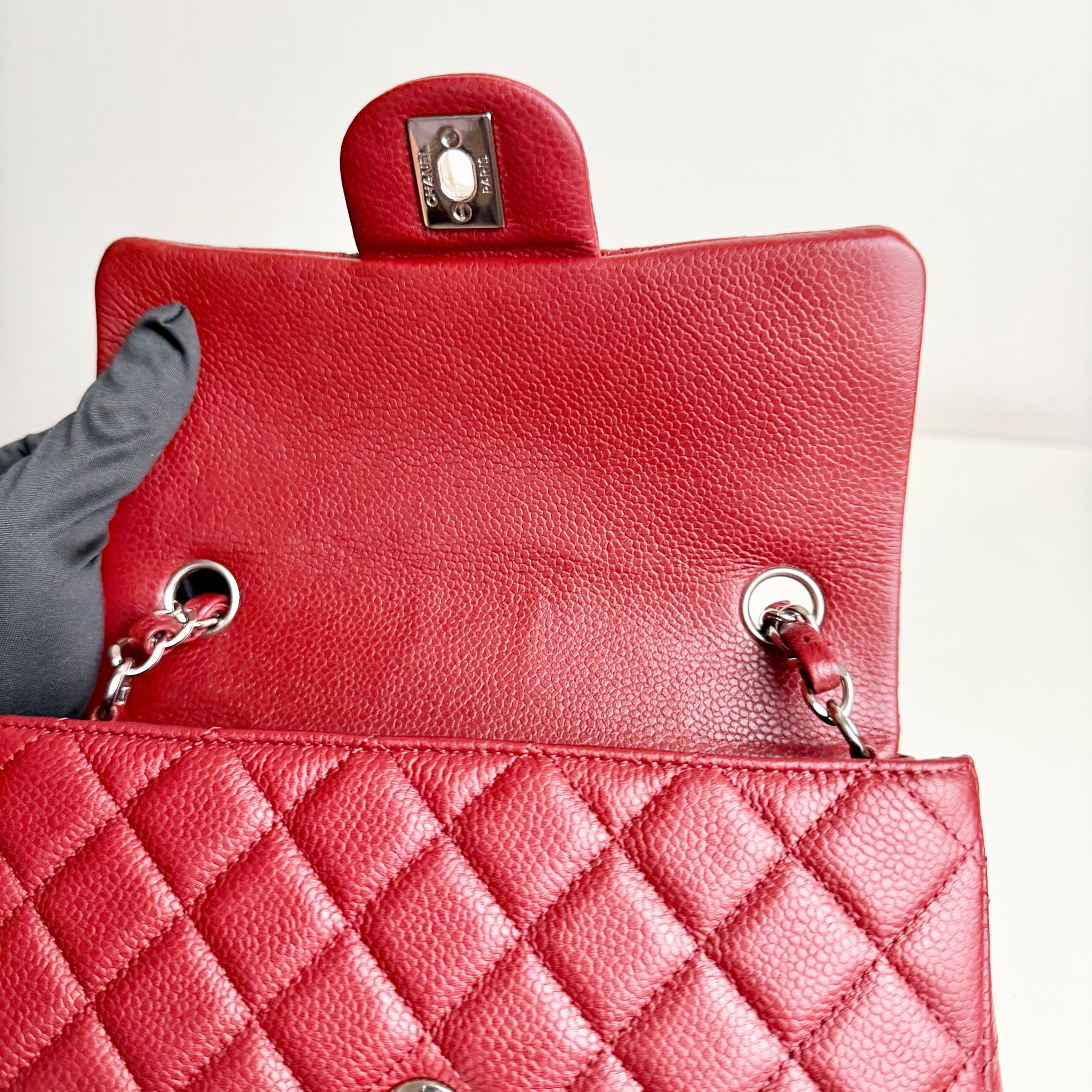 Red quilted handbag with a silver clasp on a light gray background