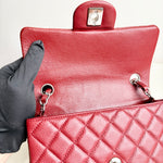 将图片加载到图库查看器，Red quilted handbag with a gloved hand holding it open.
