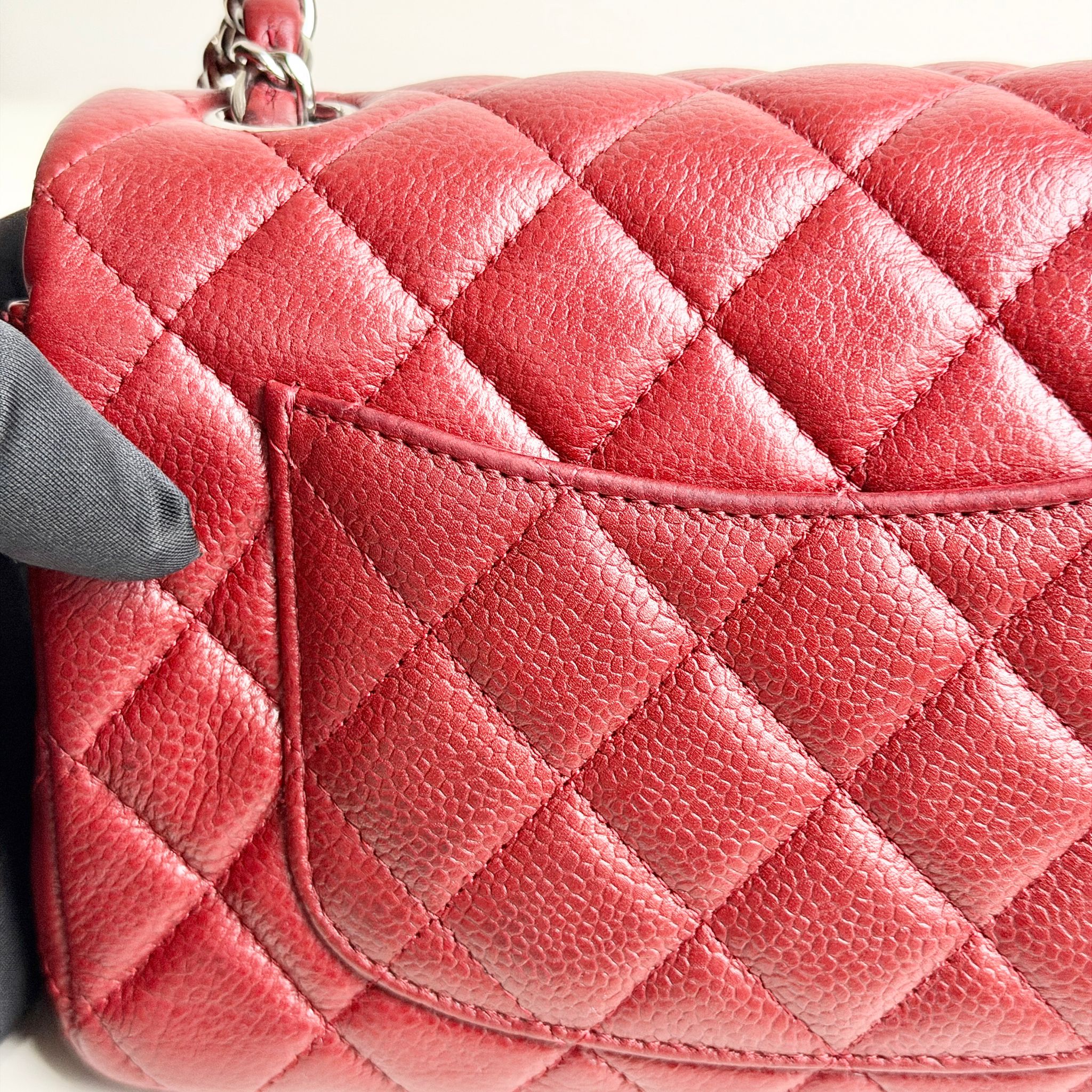 Close-up of a pink quilted handbag with a gray strap.