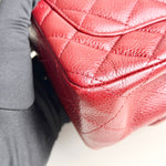 将图片加载到图库查看器，Close-up of a red quilted handbag with a blurred background
