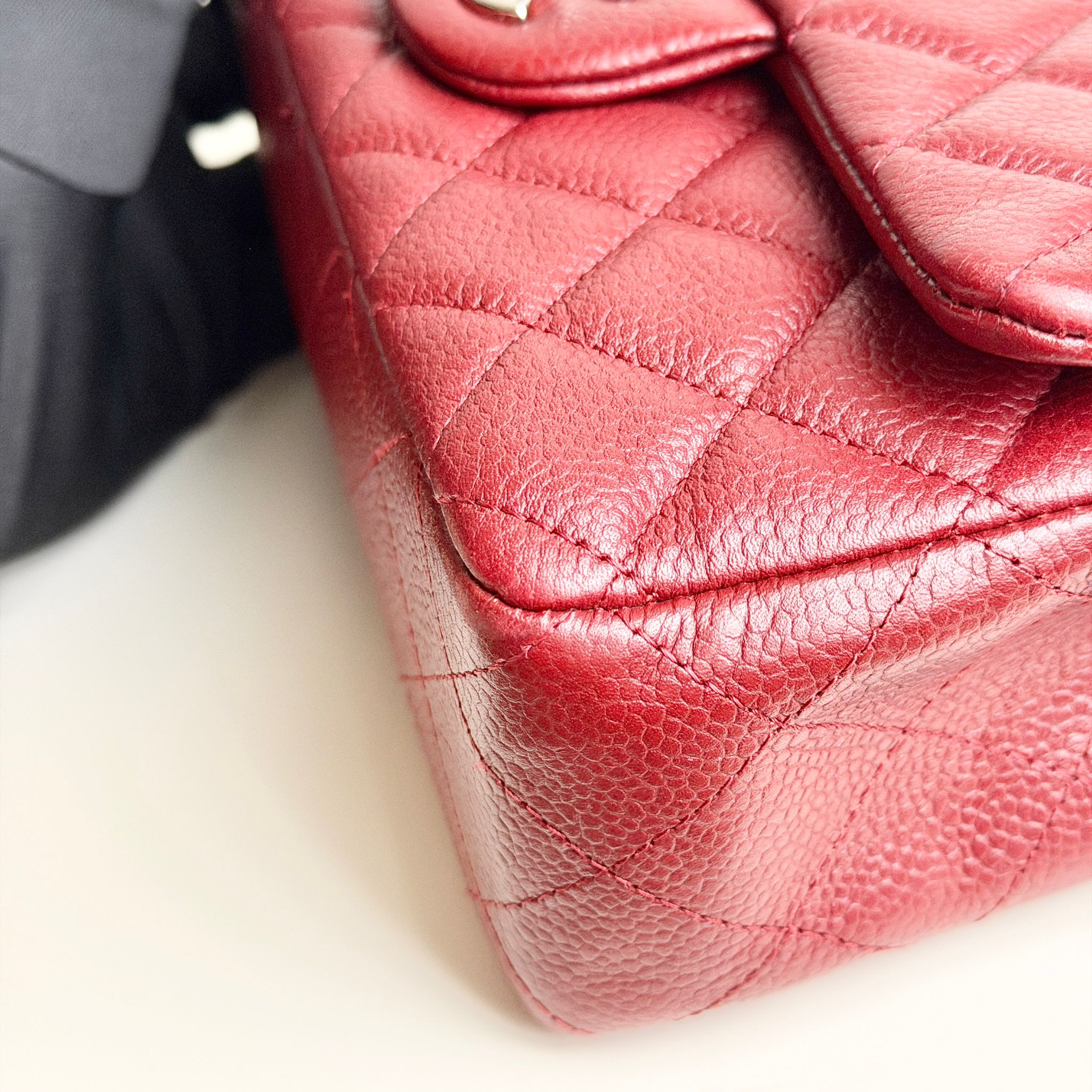 Close-up of a red quilted handbag on a white surface