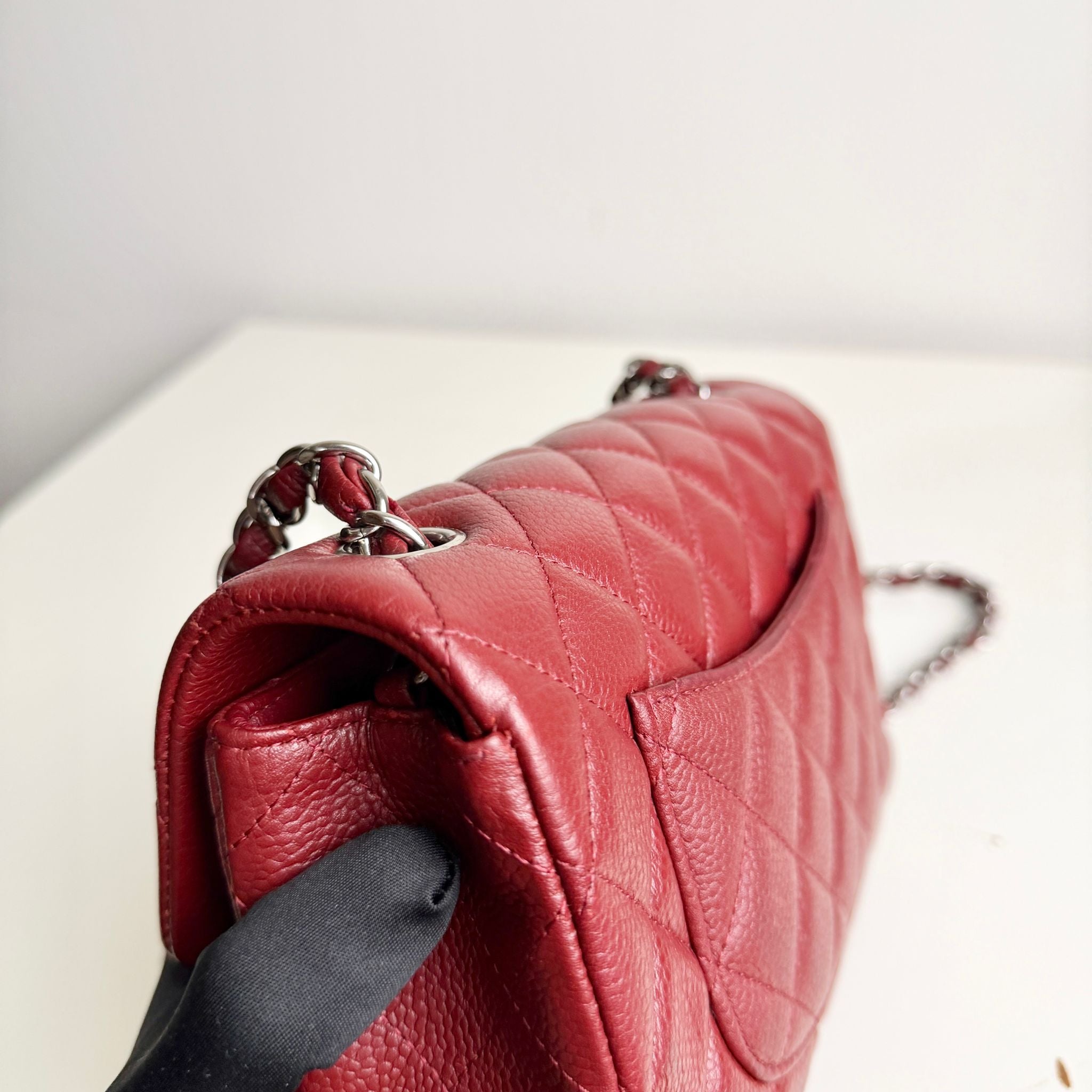 Red quilted handbag with a chain strap on a light background