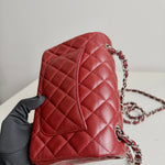 将图片加载到图库查看器，Red quilted handbag with a chain strap held by a gloved hand against a neutral background

