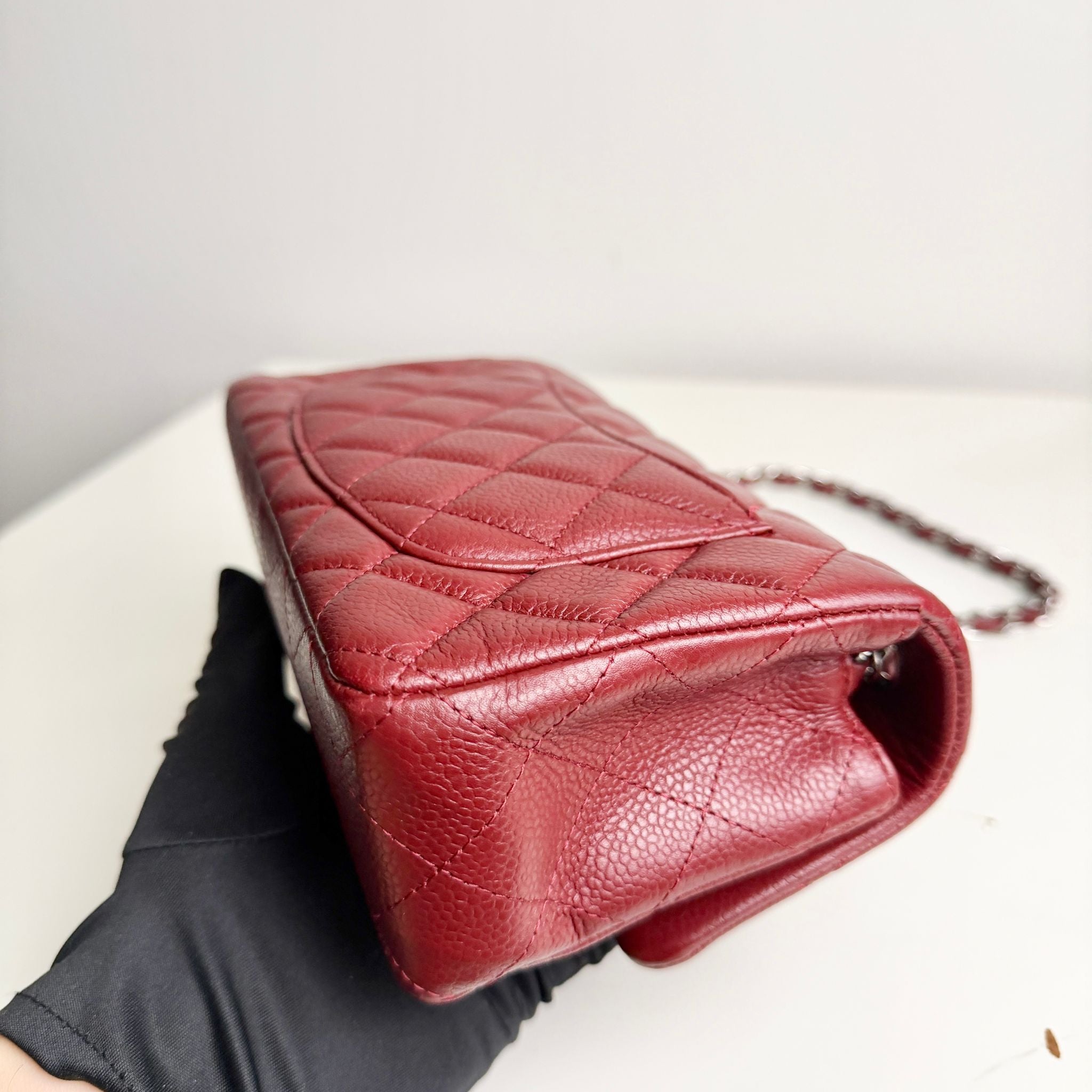 Red quilted handbag on a white surface with a neutral background