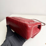 将图片加载到图库查看器，Red quilted handbag held by a gloved hand on a white surface
