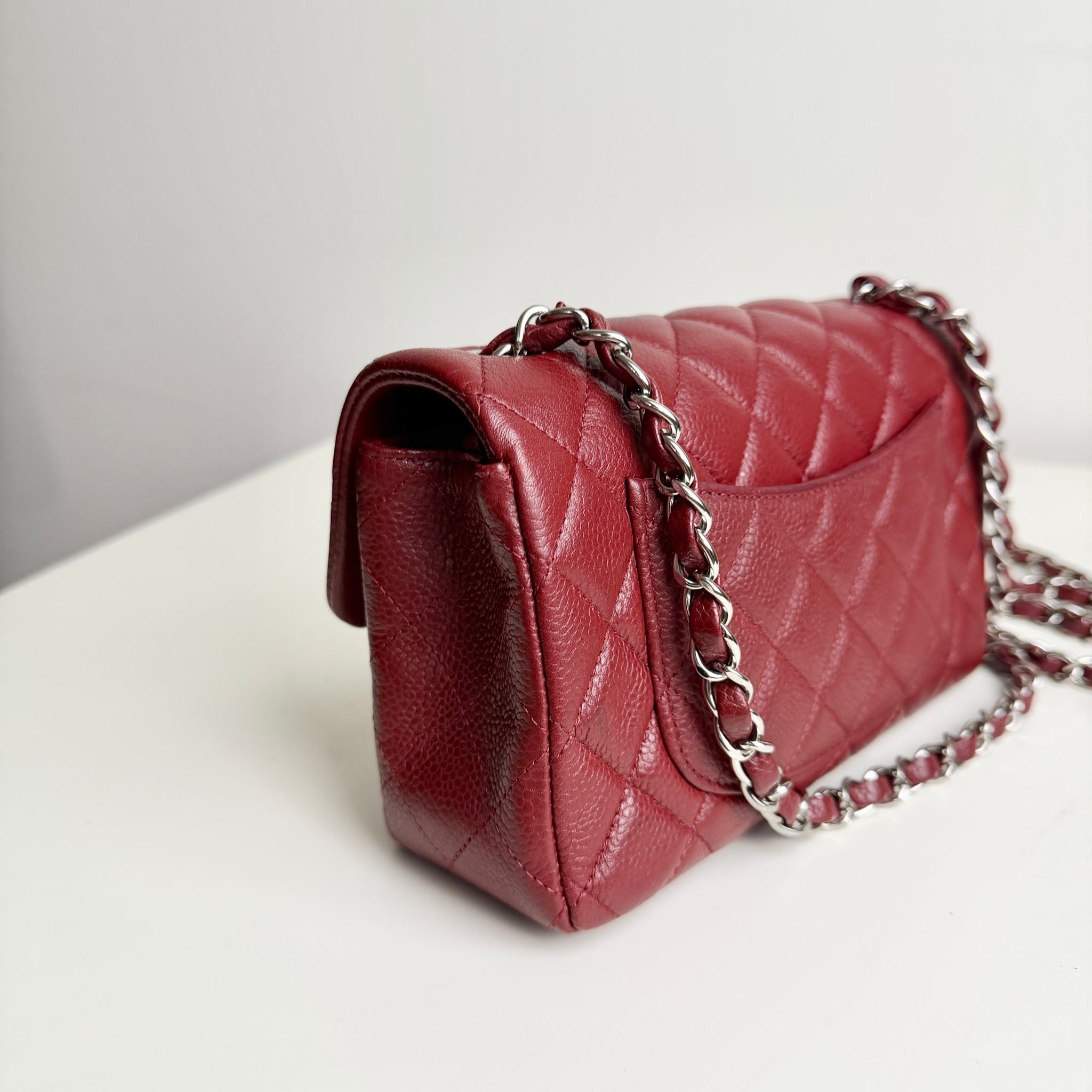 Red quilted handbag with a chain strap on a light background