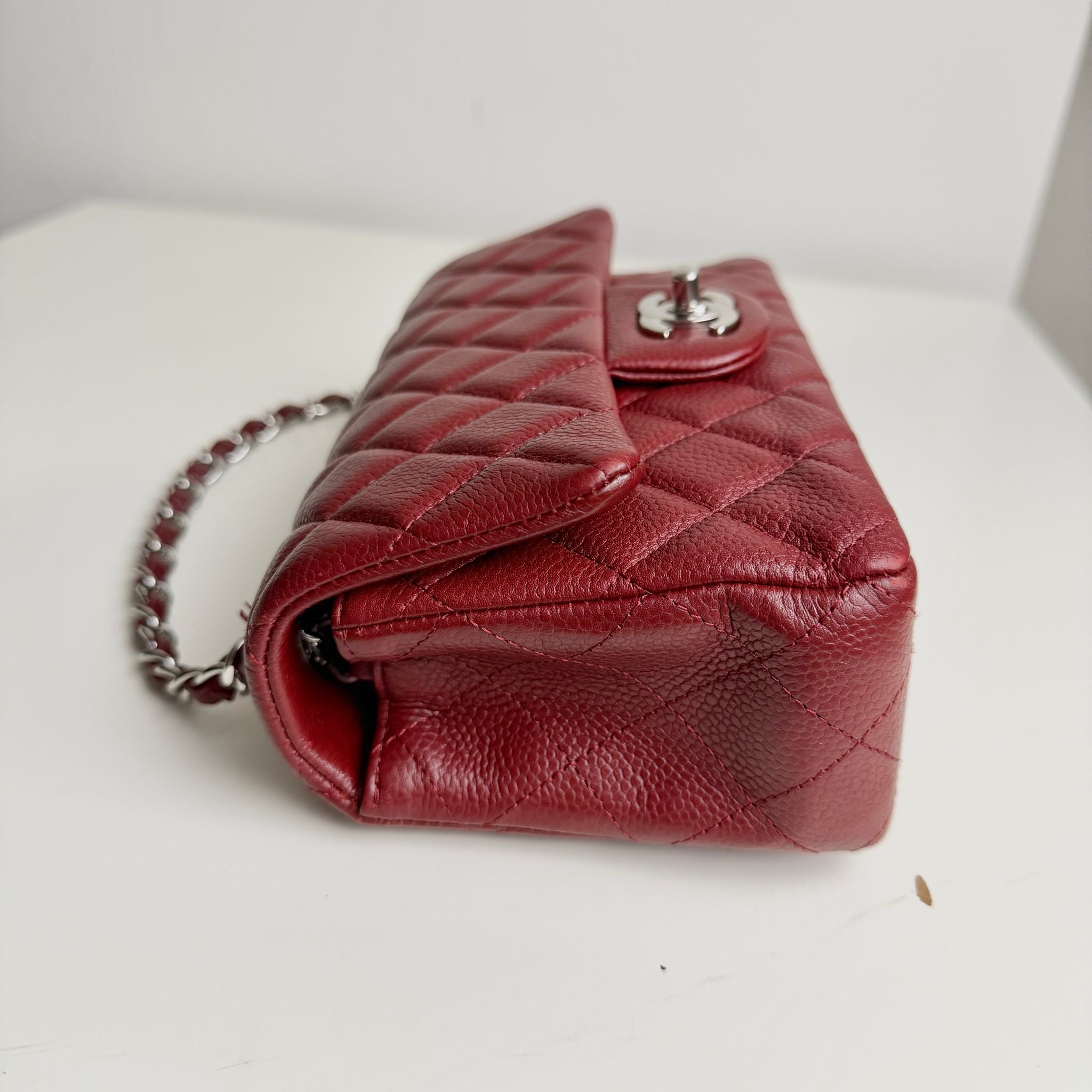 Red quilted handbag with a chain strap on a light background