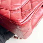 将图片加载到图库查看器，Close-up of a red quilted handbag with a blurred background

