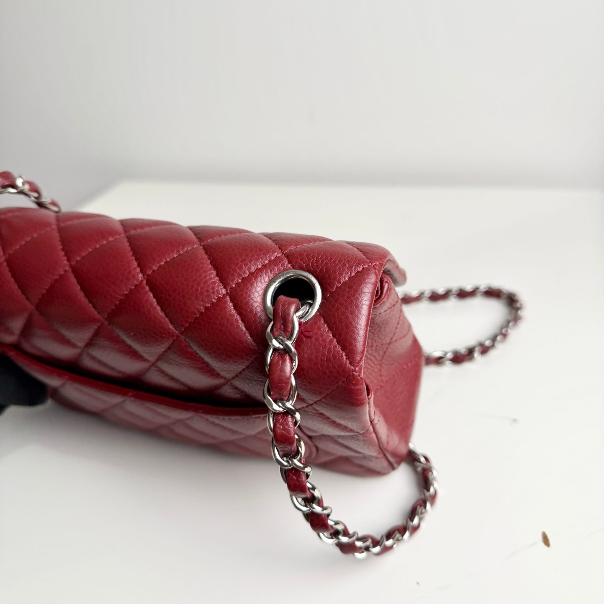 Red quilted handbag with a chain strap on a white background