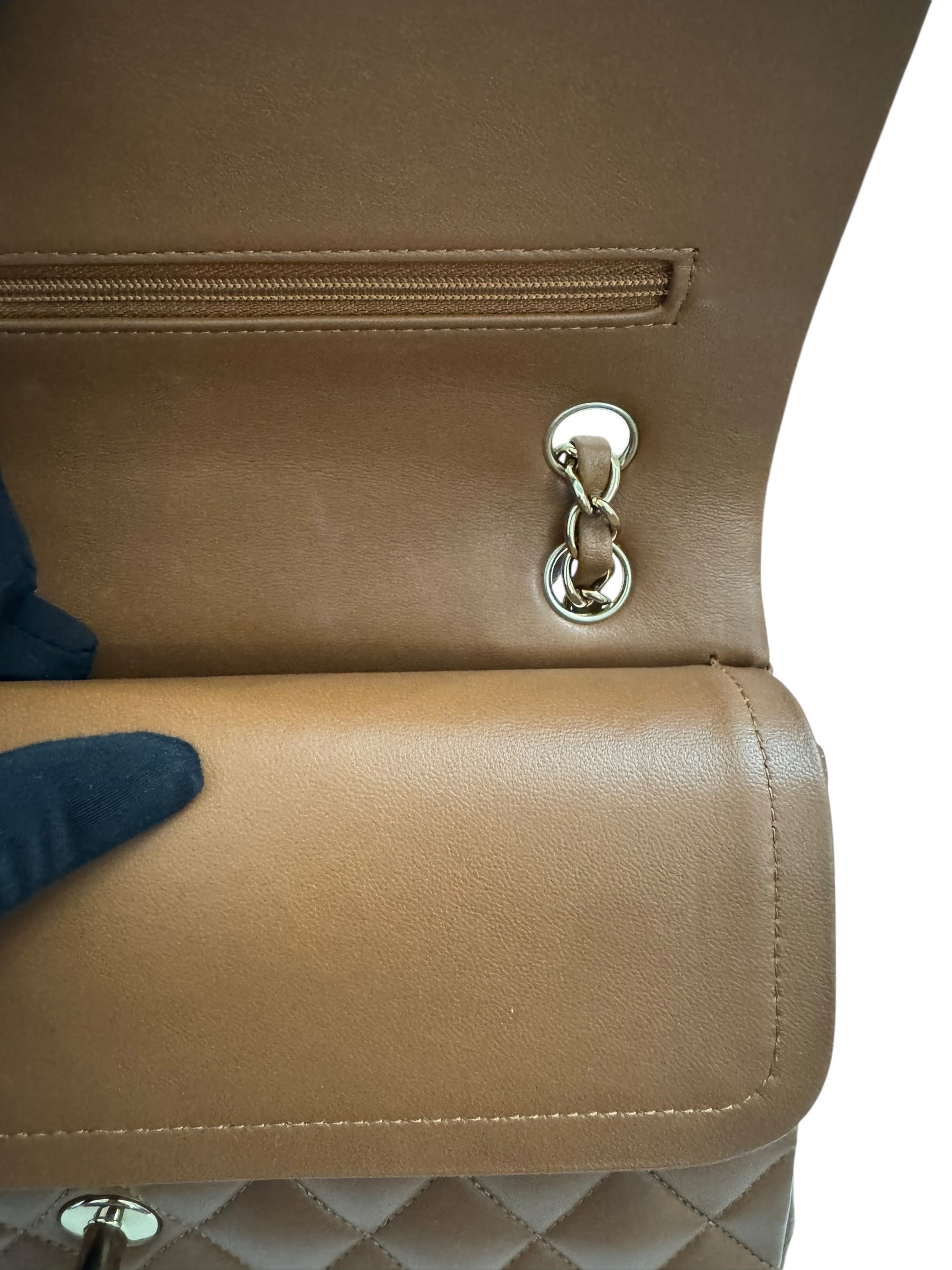 Close-up of a beige handbag with a silver clasp on a white background