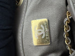 将图片加载到图库查看器，Close-up of a Chanel logo on a gray handbag with gold chain.
