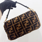 将图片加载到图库查看器，Brown handbag with black pattern held by a gloved hand on a white background
