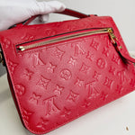 Load image into Gallery viewer, Red handbag with a prominent logo pattern held by a gloved hand on a white background
