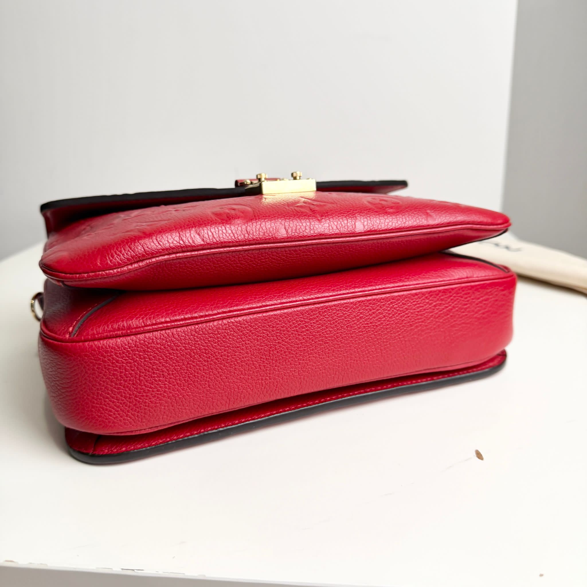 Red handbag on a white surface with a neutral background