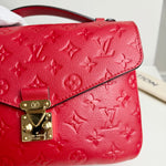 Load image into Gallery viewer, Red handbag with gold lock and Louis Vuitton monogram pattern on a white background
