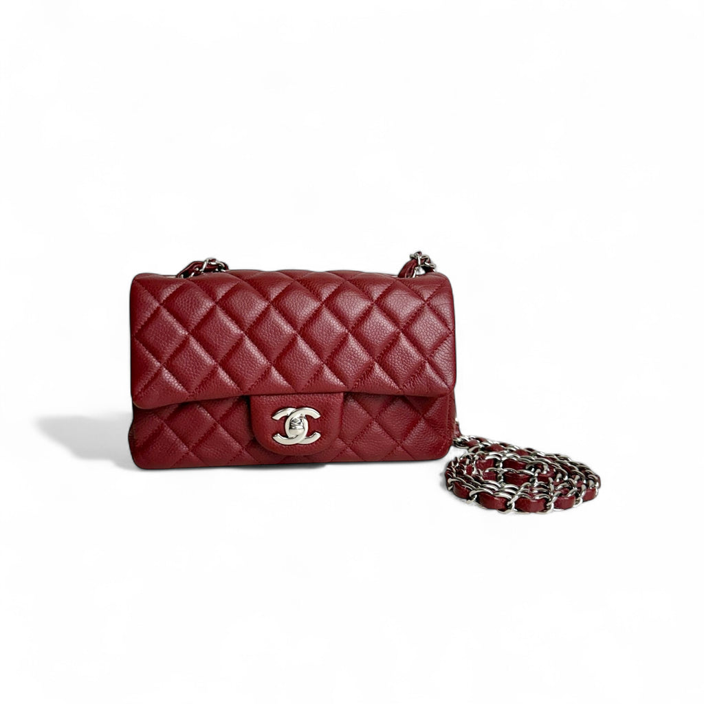 Red quilted handbag with chain strap on a white background