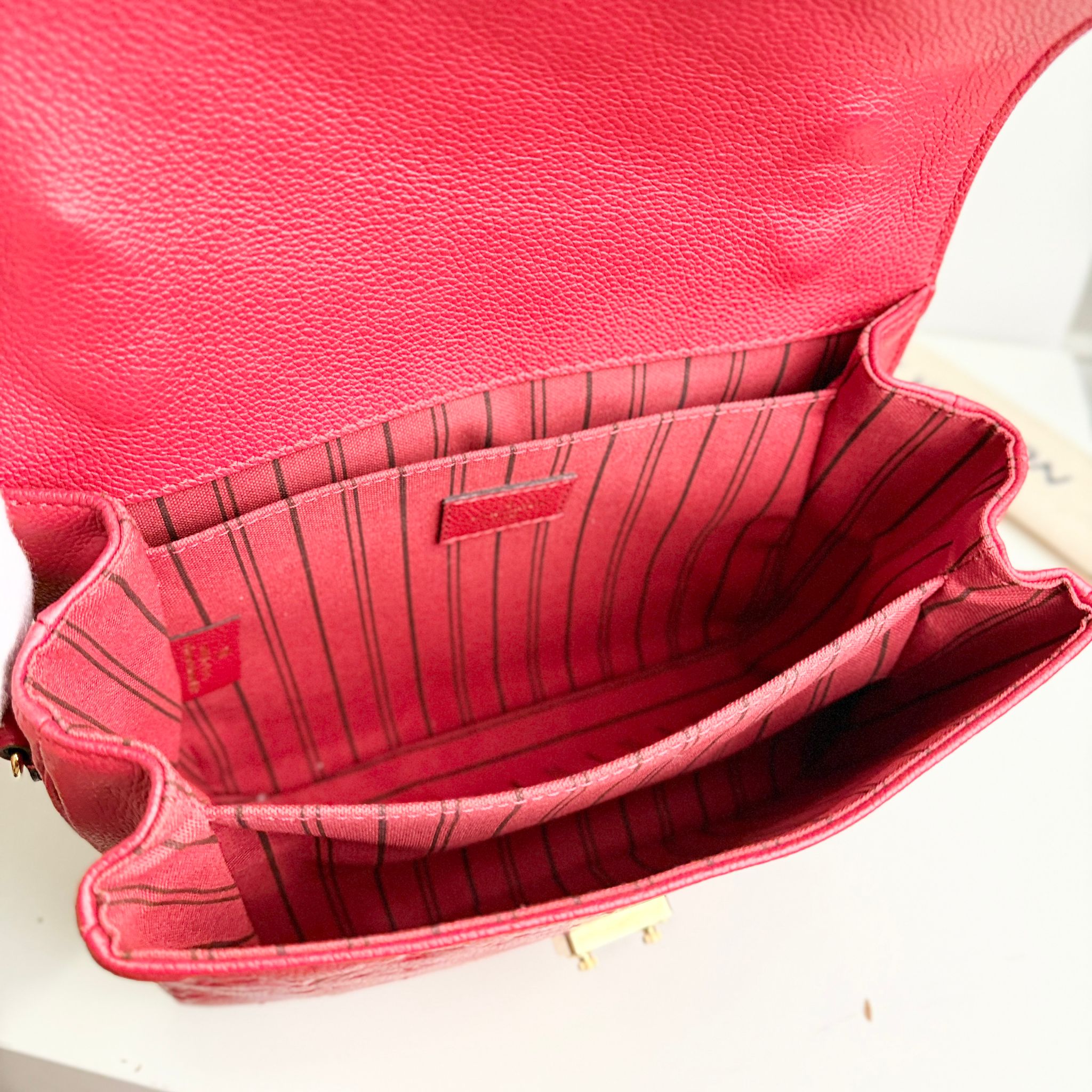 Close-up of a red handbag with visible brand logo on a white background
