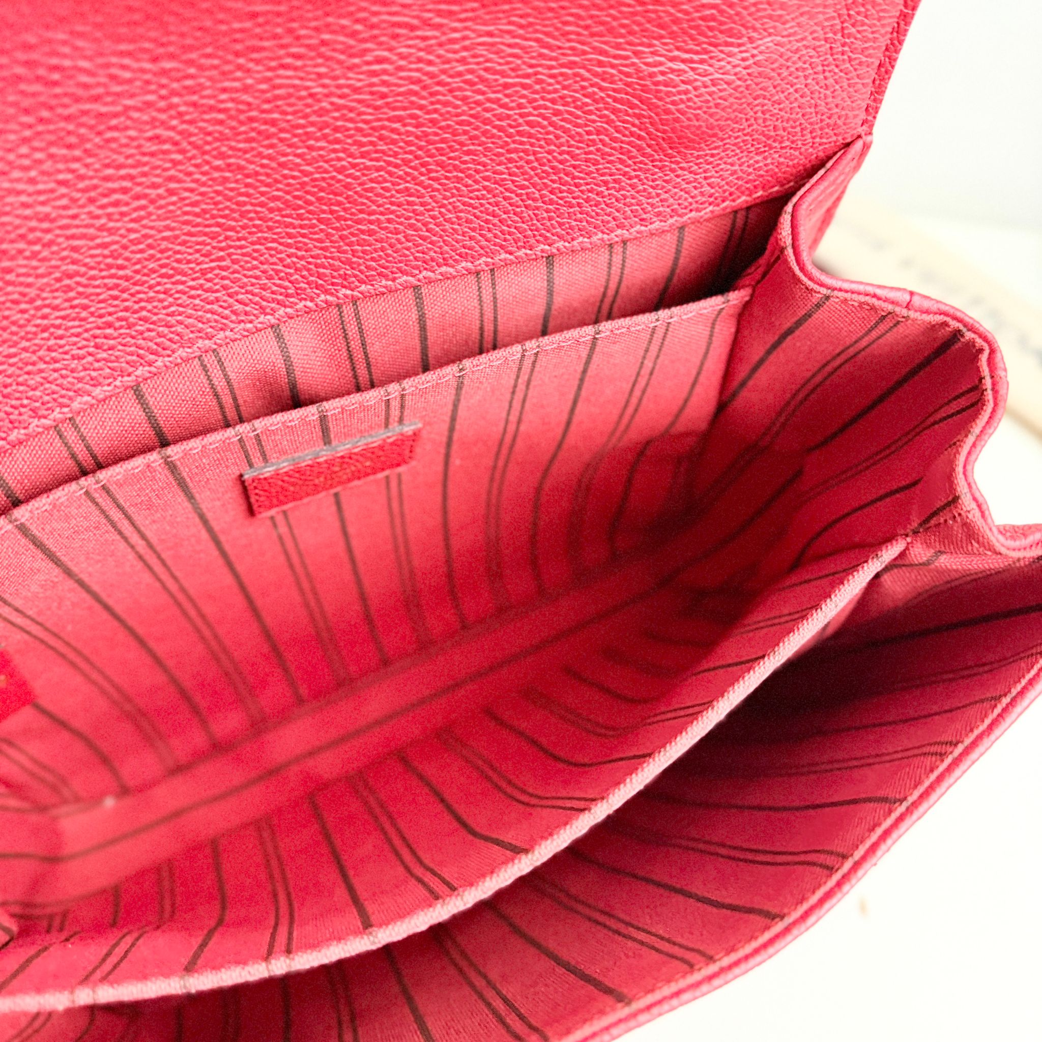 Close-up of a red leather handbag with visible stitching