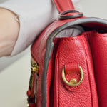Load image into Gallery viewer, Close-up of a red leather handbag with gold hardware.
