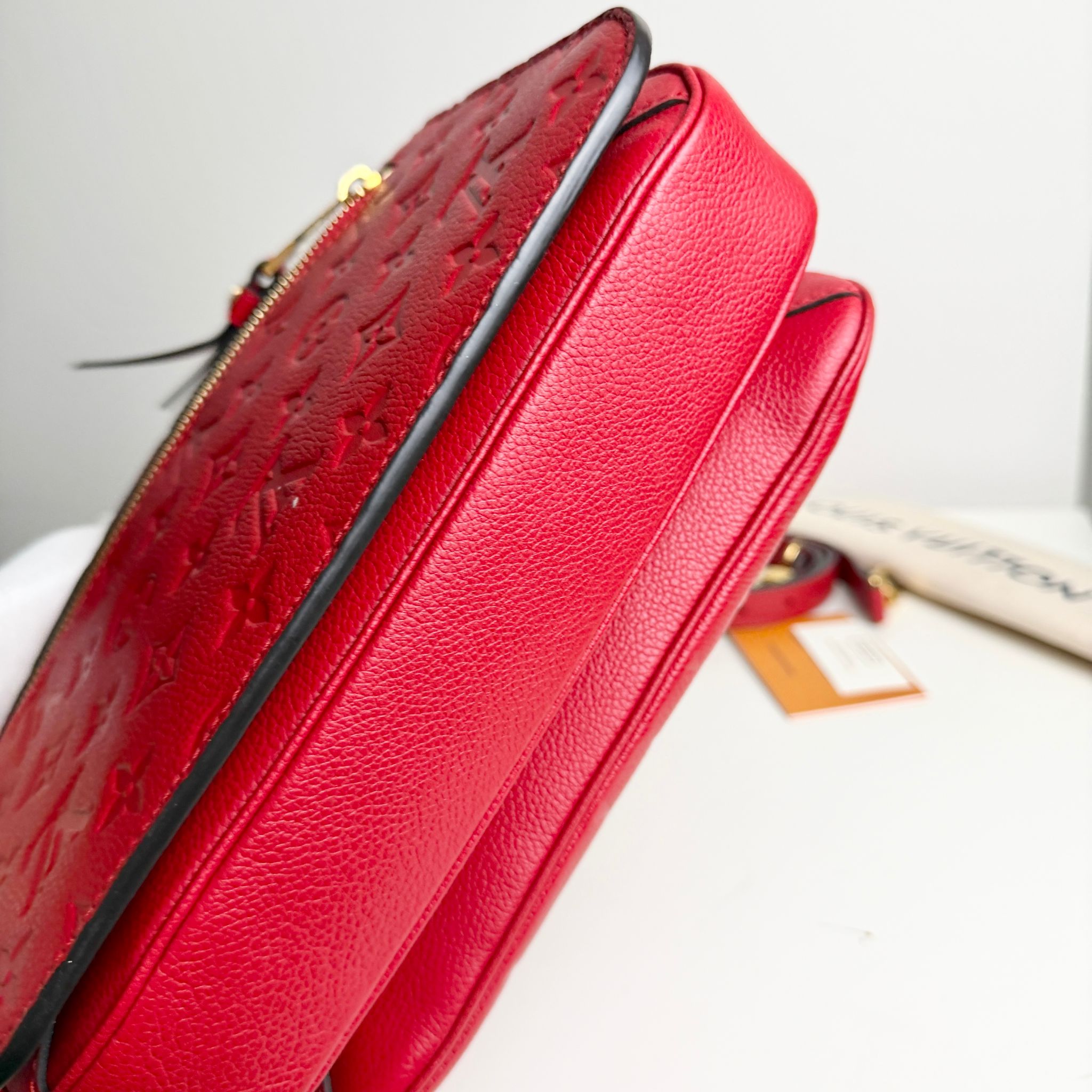 Red textured handbag with a visible brand tag on a light background