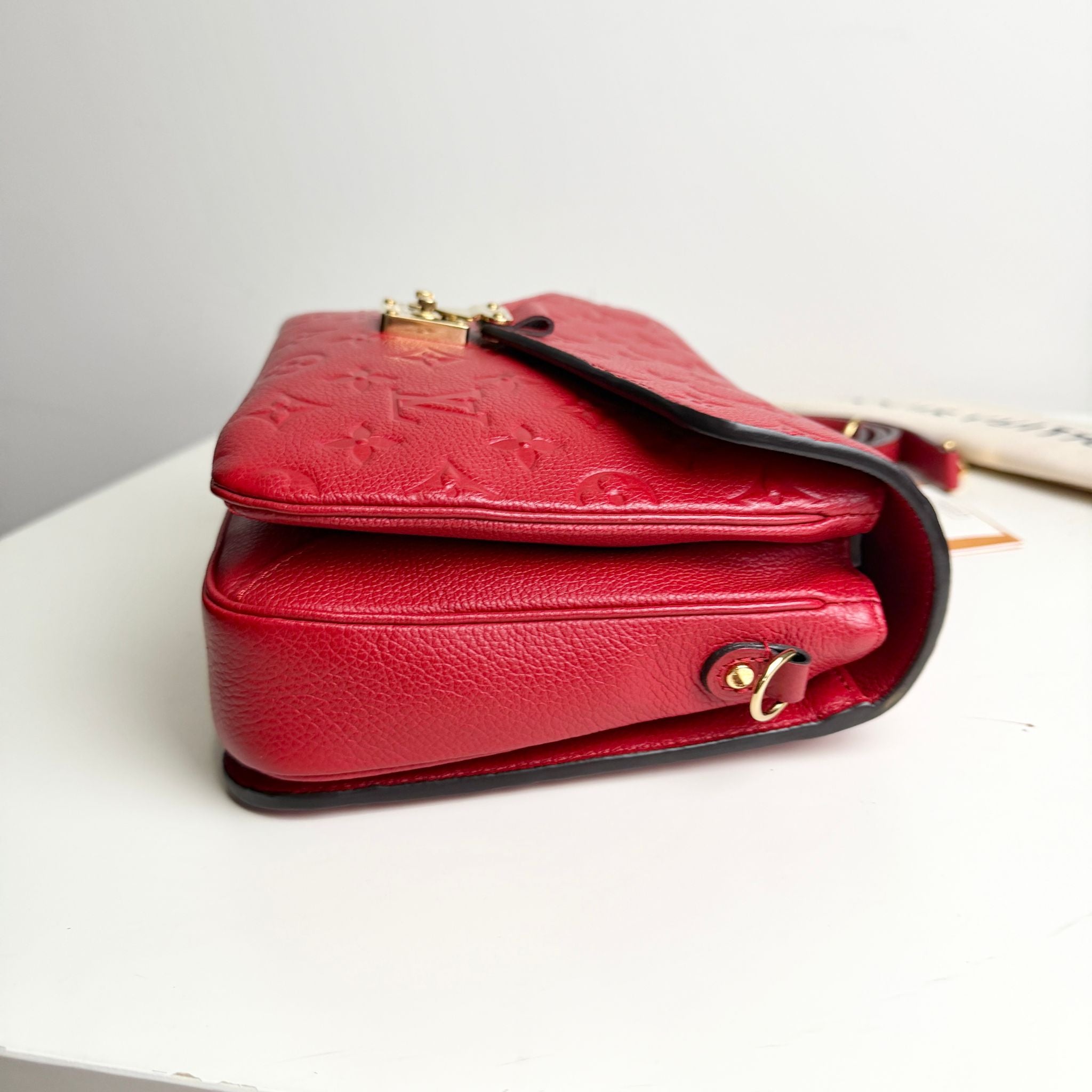 Red handbag with gold accents on a light gray background