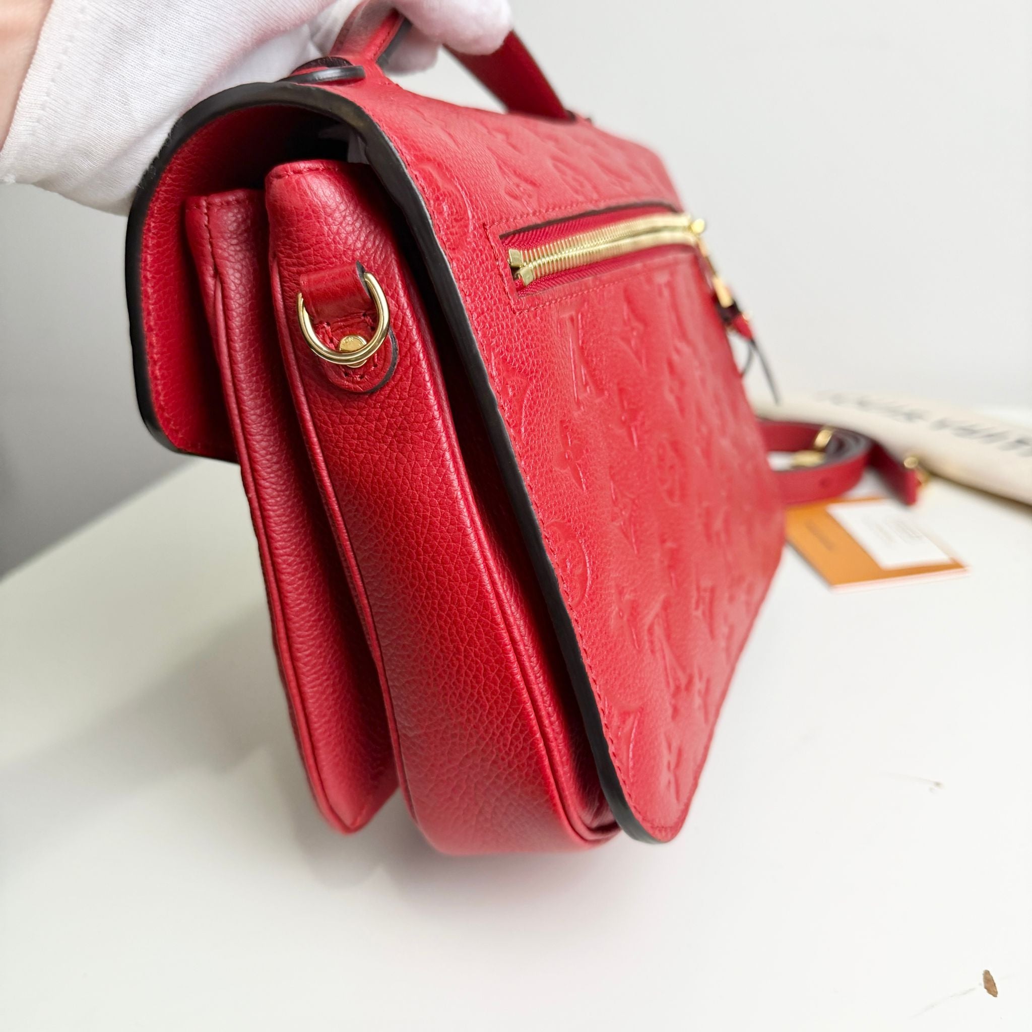 Red handbag with gold zipper on a white surface