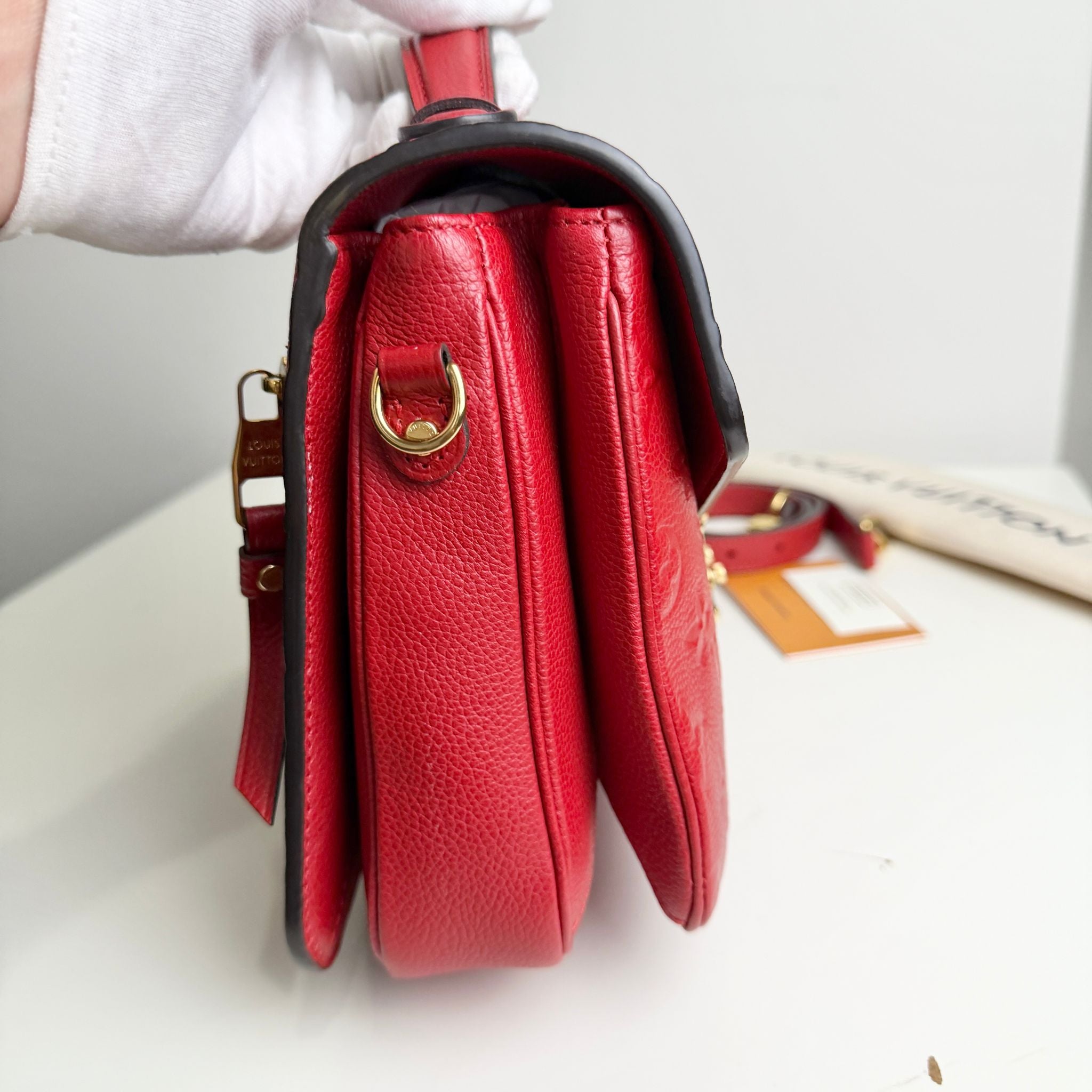 Red handbag with gold clasp on a white surface