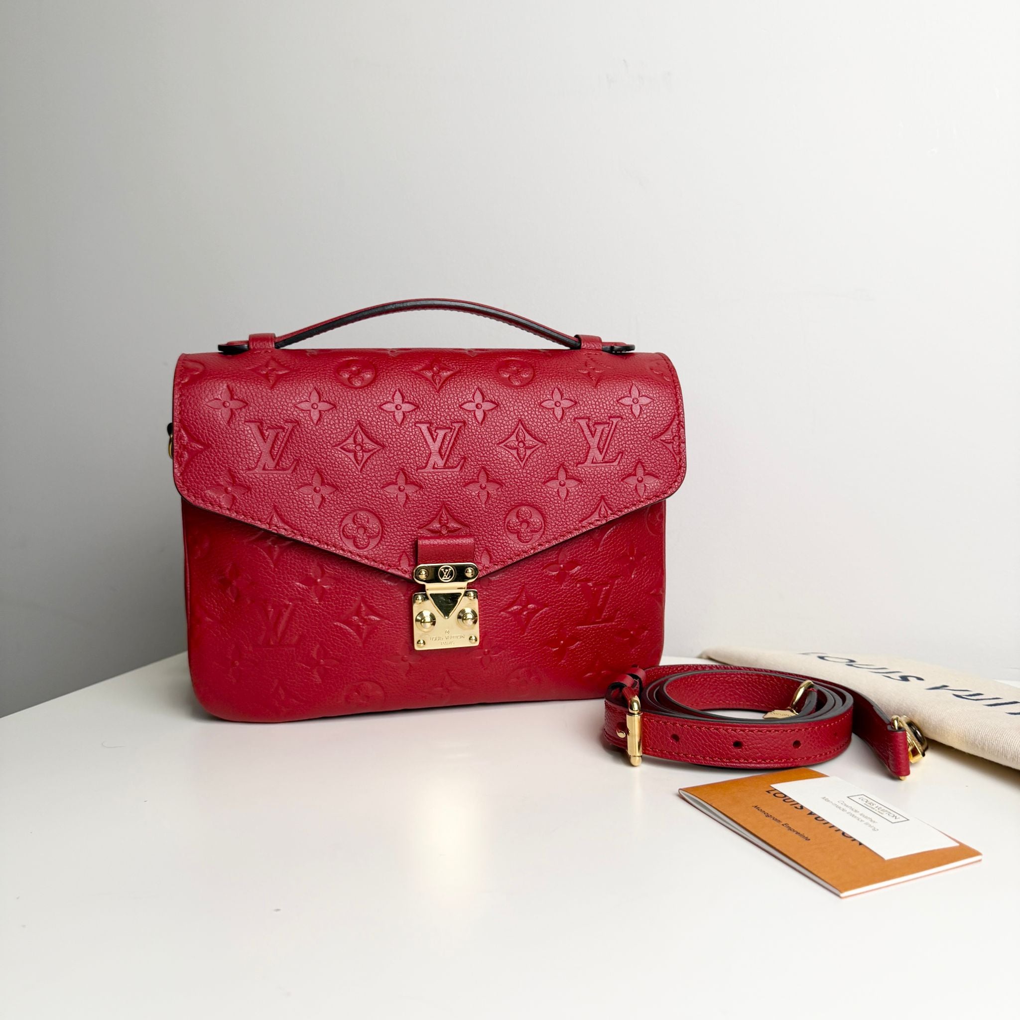 Red handbag with monogram pattern on a white surface